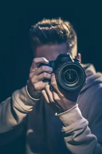 تصویر یک مرد عکاس با دوربین در تاریکی عکس می گیرد